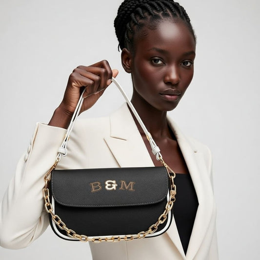 Woman holding a black handbag with gold chain detail against a white background