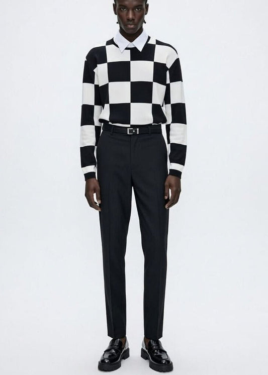 Person wearing a black and white checkered shirt with black pants on a white background