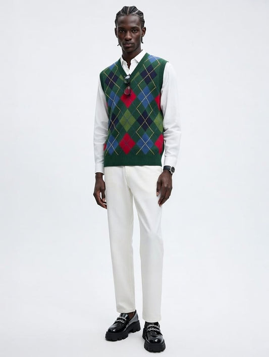 Man wearing a patterned vest over a white shirt with white pants on a light gray background